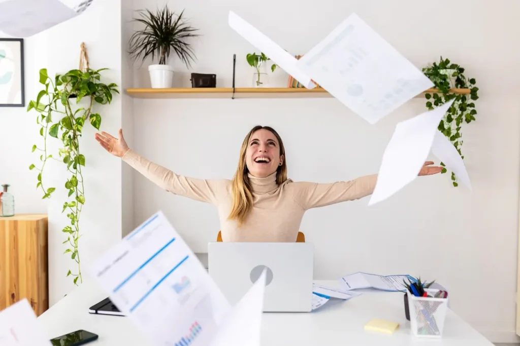 une femme à son bureau motivée par le succès et heureuse , bras ouverts