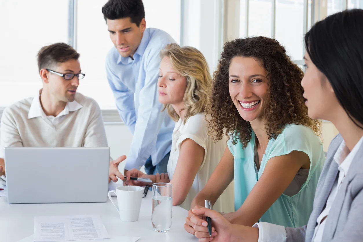 Femme souriante entourée de collaborateurs en groupe de travail